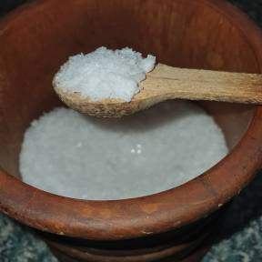 Coarse sea salt crystals in a wooden bowl
